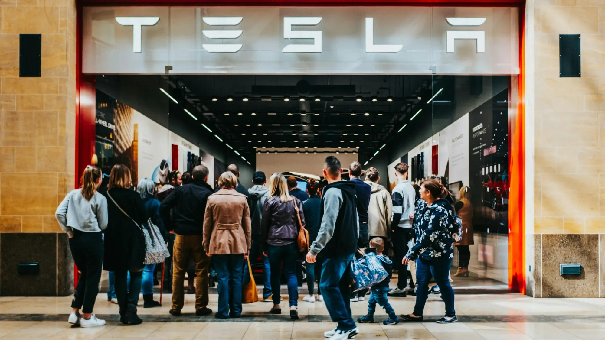 Grupo de personas haciendo fila frente a la entrada de una tienda Tesla